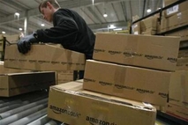 A worker carries packages for shipment at the Amazon warehouse in Leipzig,